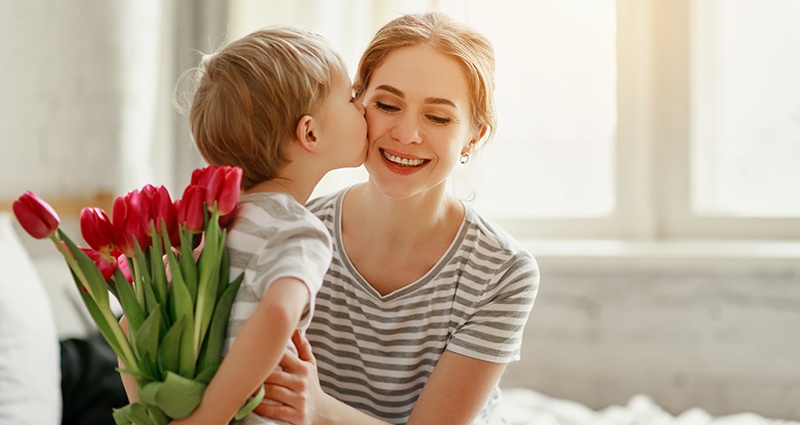 A boy giving his mother flowers and wishing all the best on Mothers Day